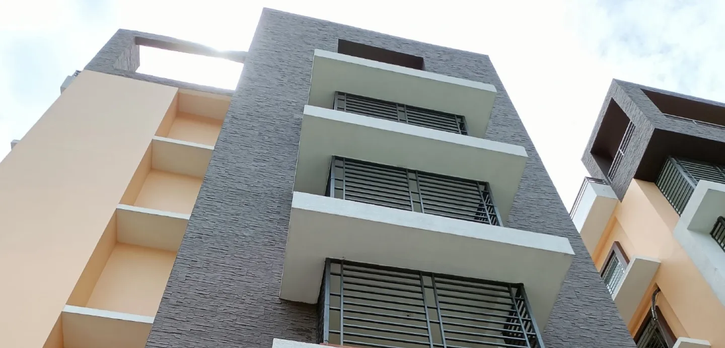 Residential facade with a dark stacked-stone cladding column and white balcony slabs