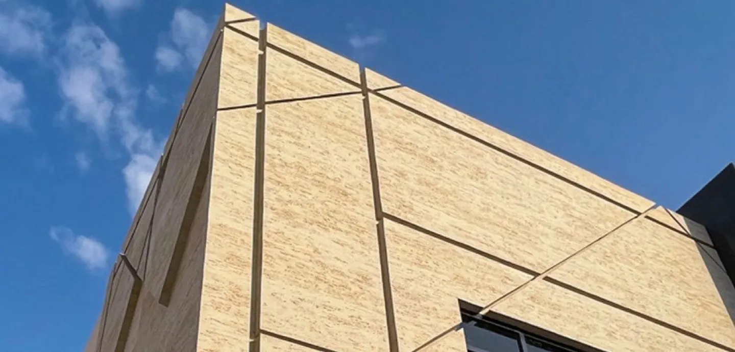 Beige travertine-look cladding with recessed geometric joints on a building corner